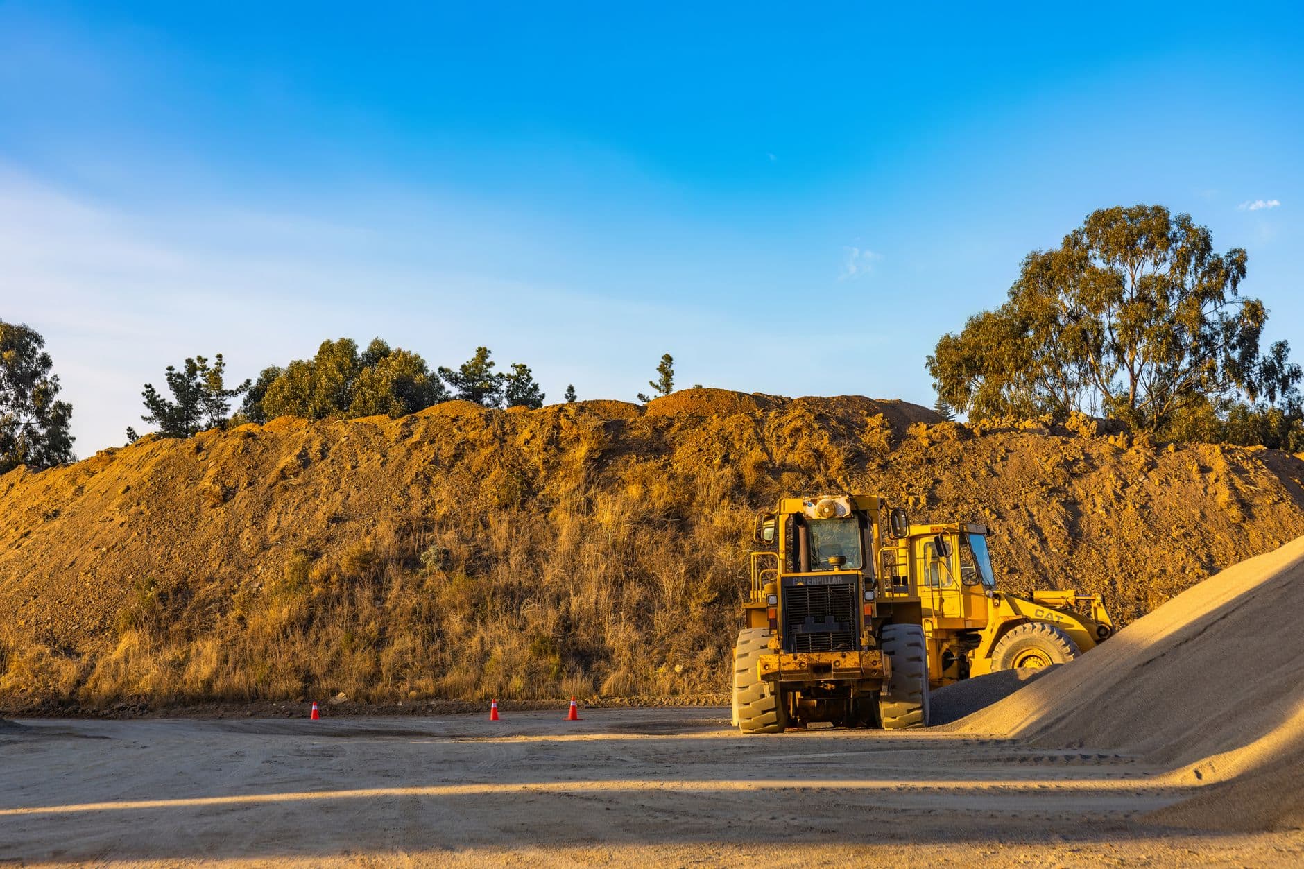 A pile of clean washed sand at a construction site with a concrete mixer in the background